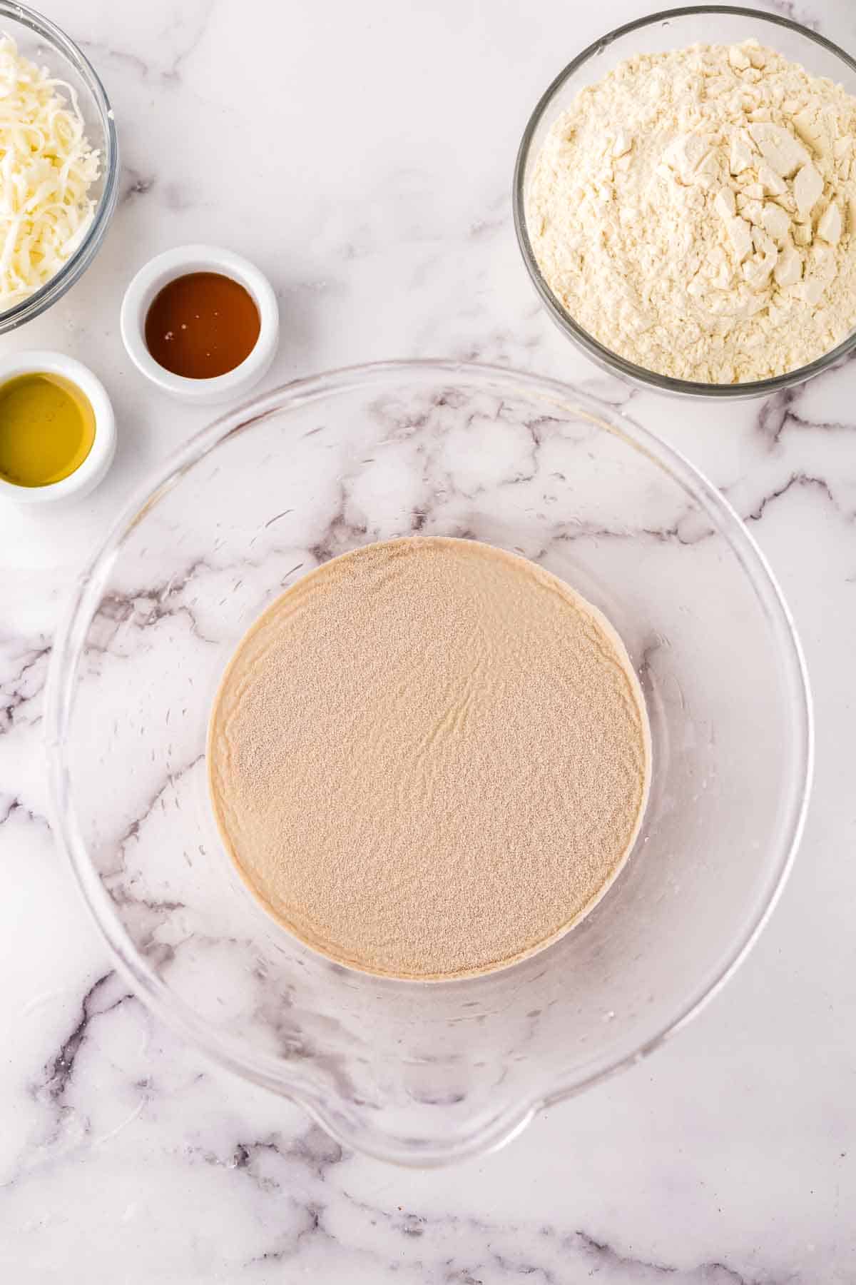 clear mixing bowl showing the progress of making pizza dough.