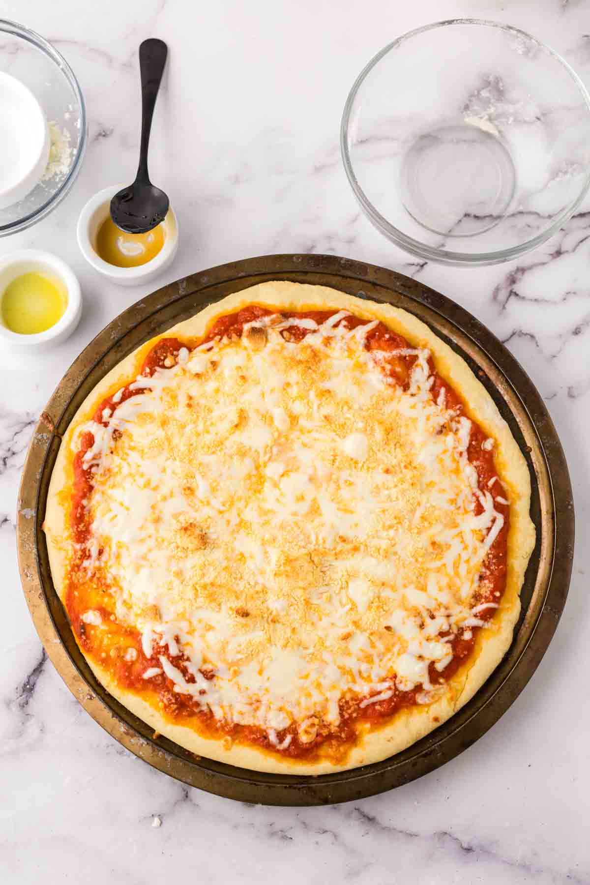 baked cheese pizza recipe on a round baking sheet.