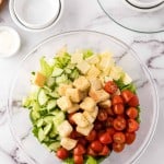 clear mixing bowl showing the progress of making a chefs salad.