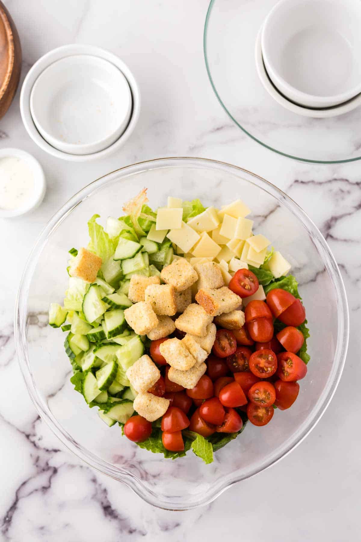 clear mixing bowl showing the progress of making a chefs salad.