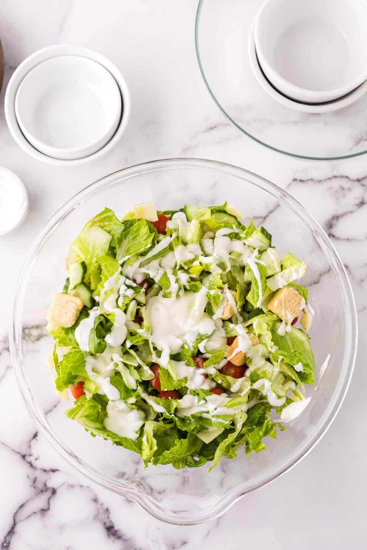 clear mixing bowl showing the progress of making a chefs salad.