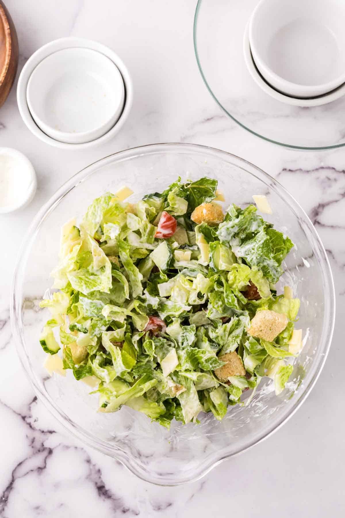 clear mixing bowl showing the progress of making a chefs salad.