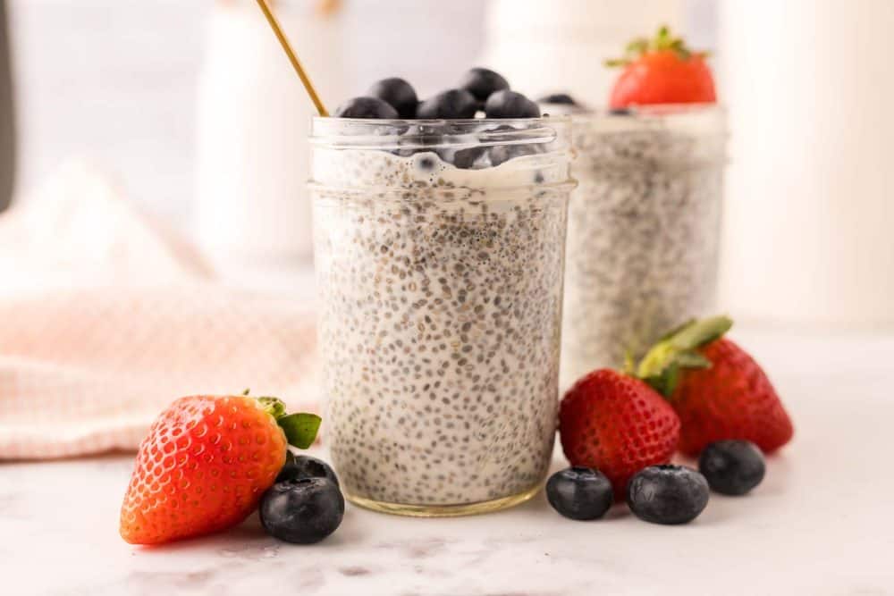 chia seed pudding in small mason jars with strawberries and blueberries.