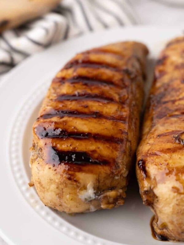 marinaded grilled chicken breasts on a white plate.