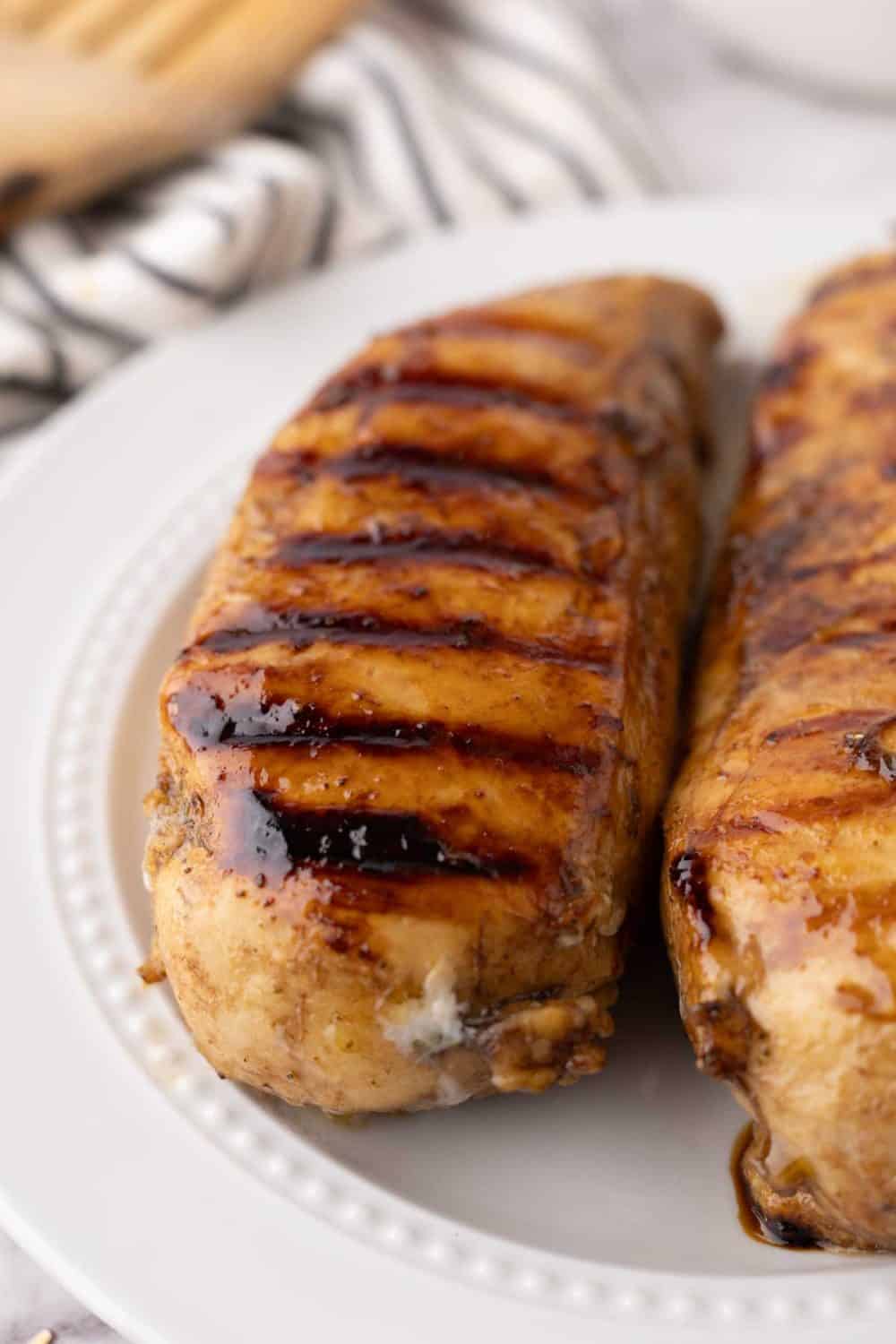 marinaded grilled chicken breasts on a white plate.