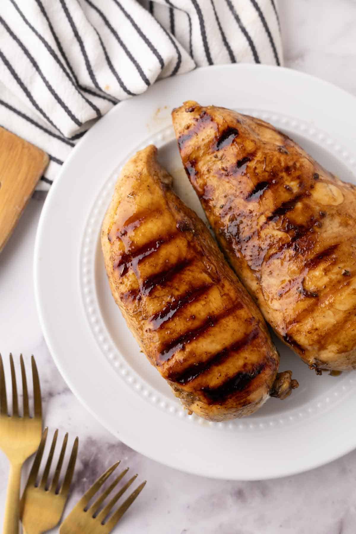 marinaded grilled chicken breasts on a white plate.