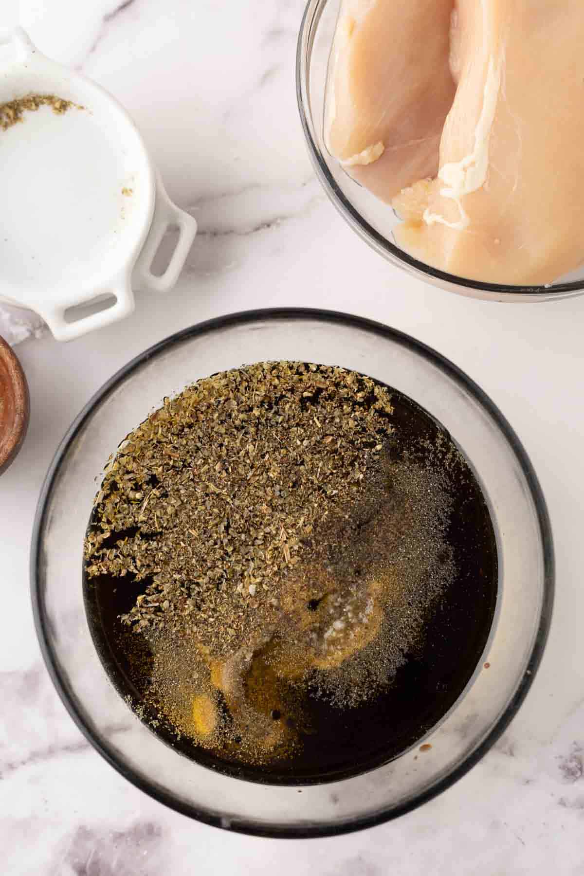 clear mixing bowl of chicken marinade ingredients in progress.