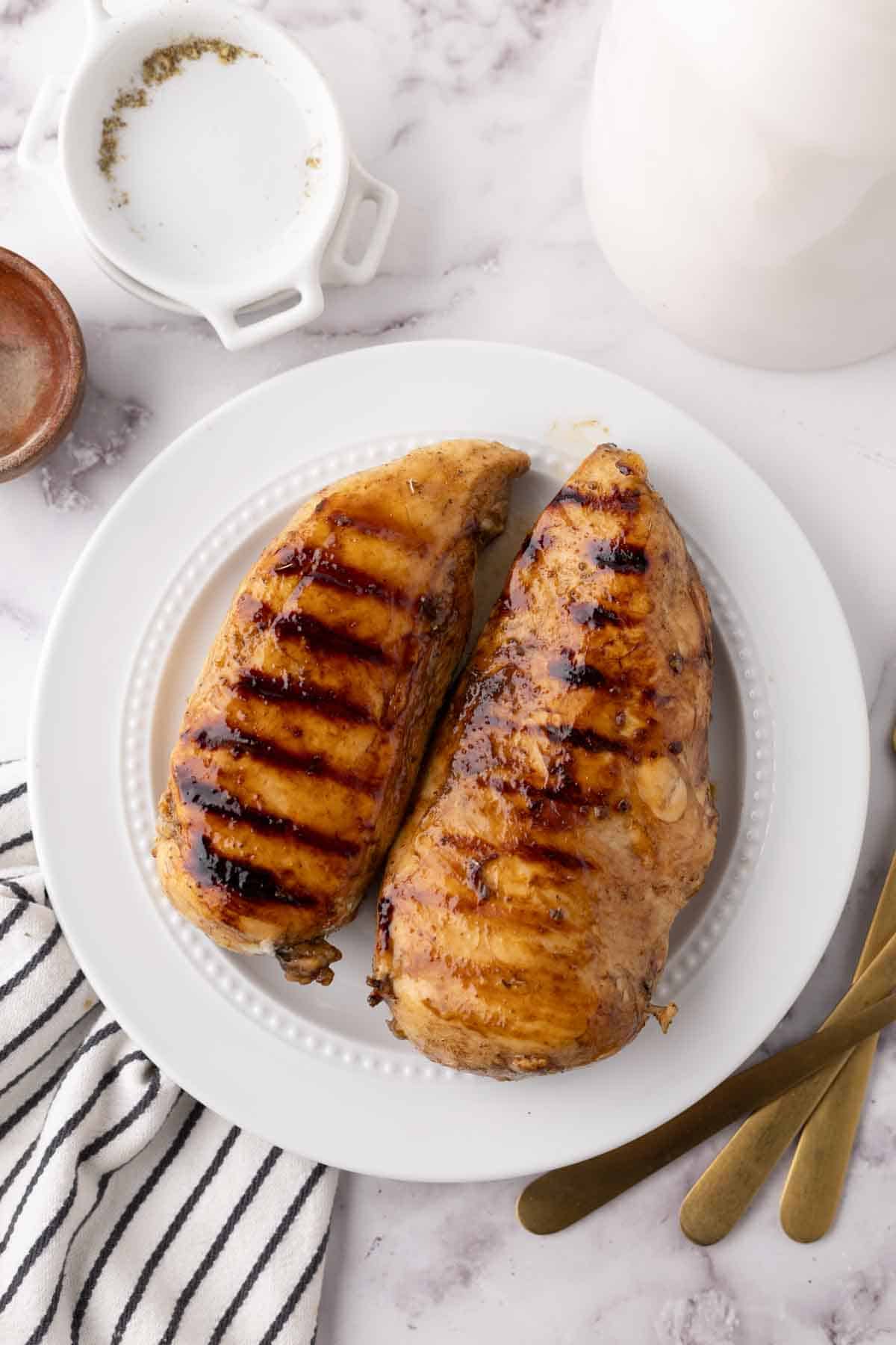 marinaded grilled chicken breasts on a white plate.