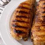 marinaded grilled chicken breasts on a white plate.