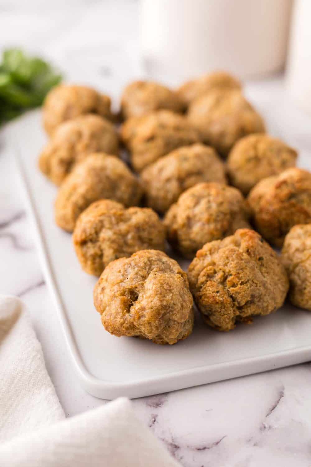 chicken meatballs lined on a rectangle cutting board.