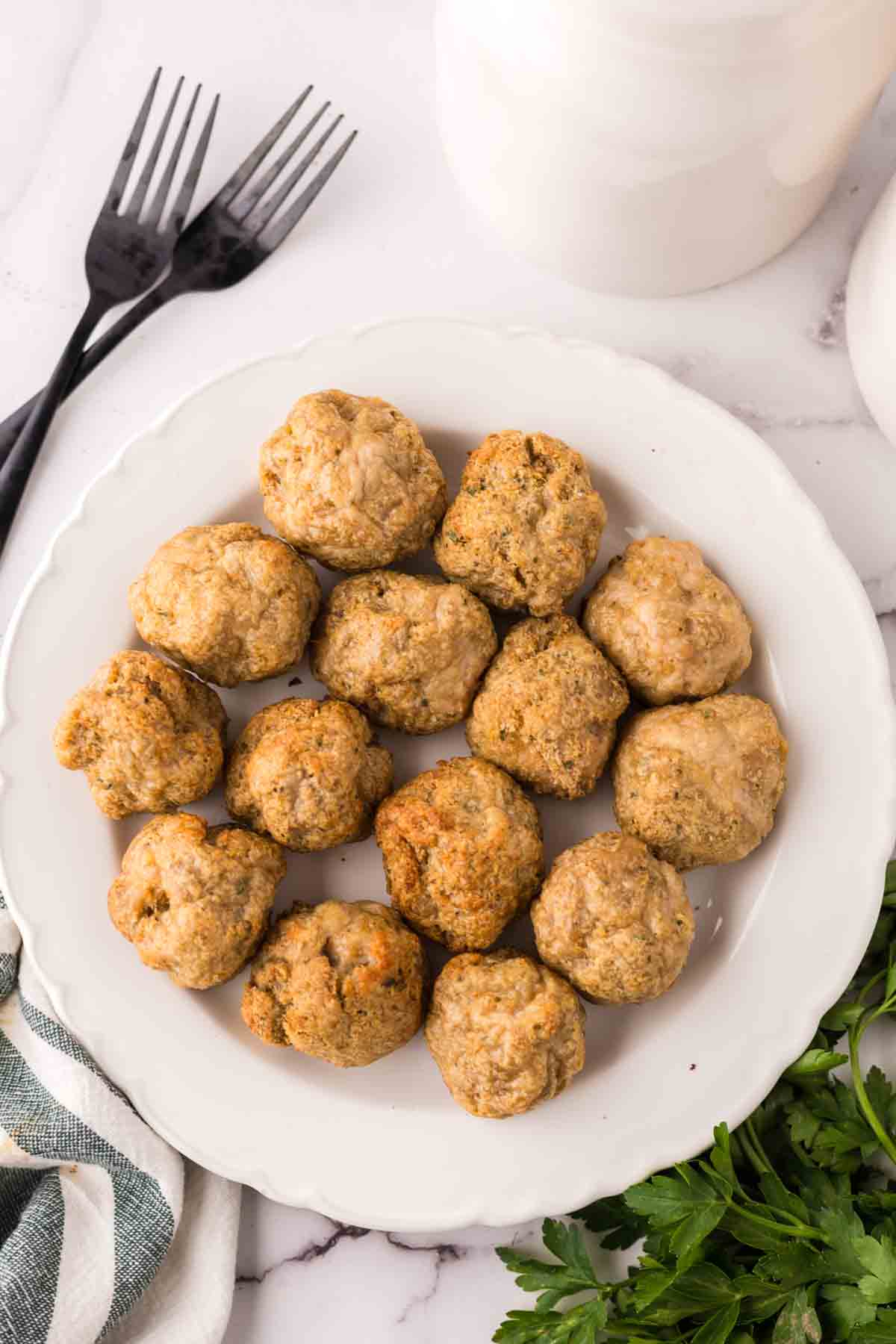 chicken meatballs on a round white plate with black forks.