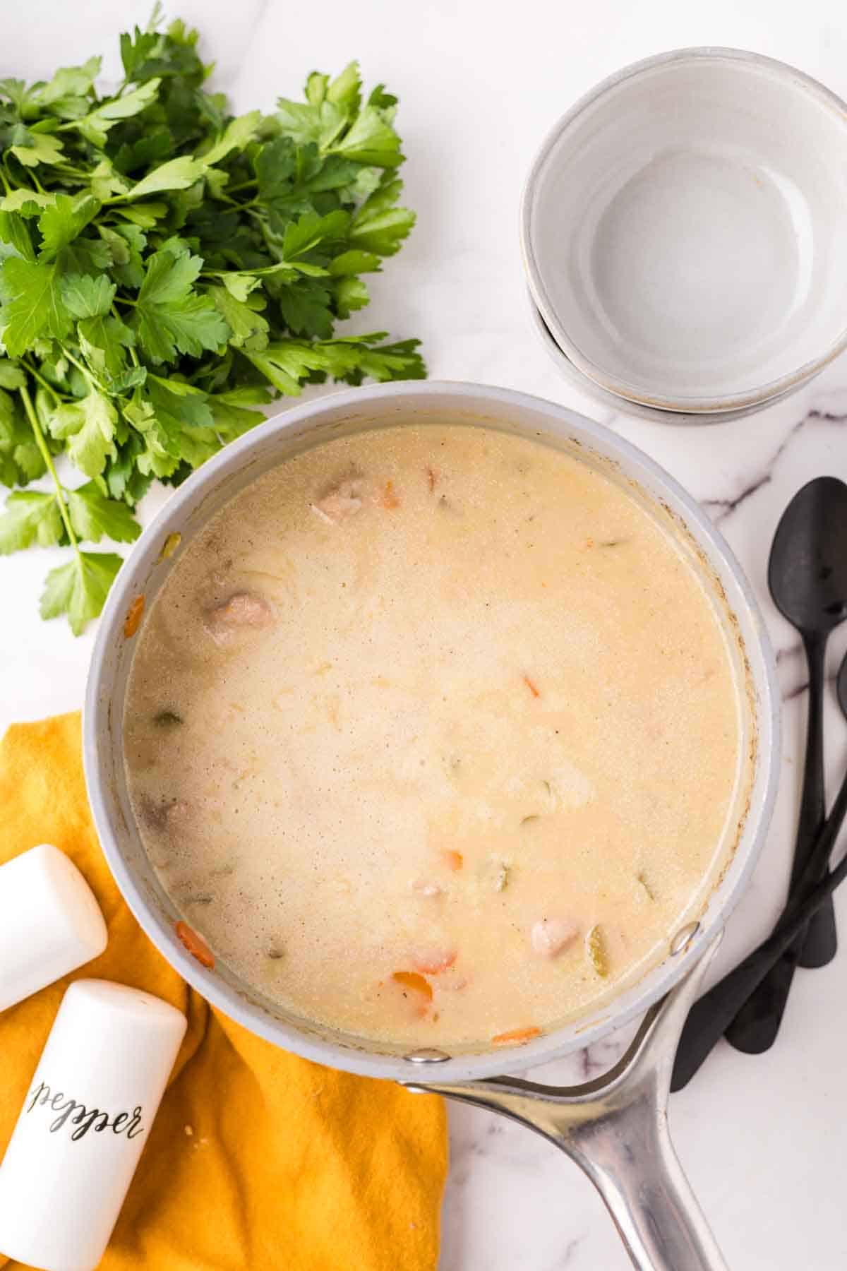 large cooking pot of chicken wild rice soup with black spoons to the side.