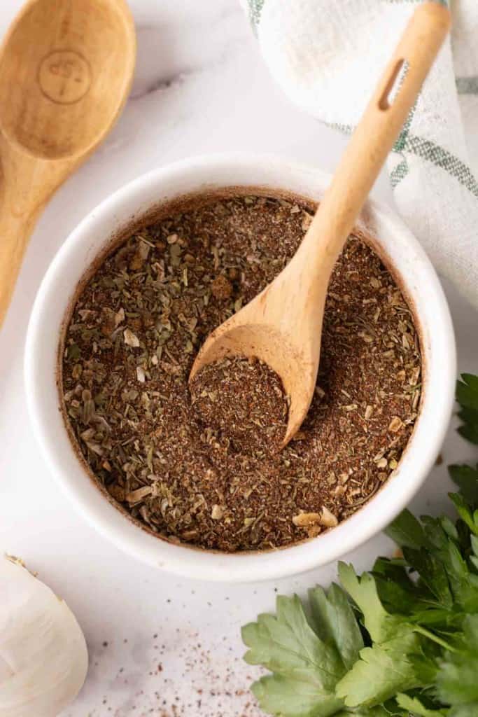 small white bowl with chili seasoning and a cute wooden spoon.