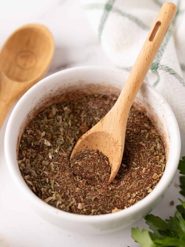 small white bowl with chili seasoning and a cute wooden spoon.