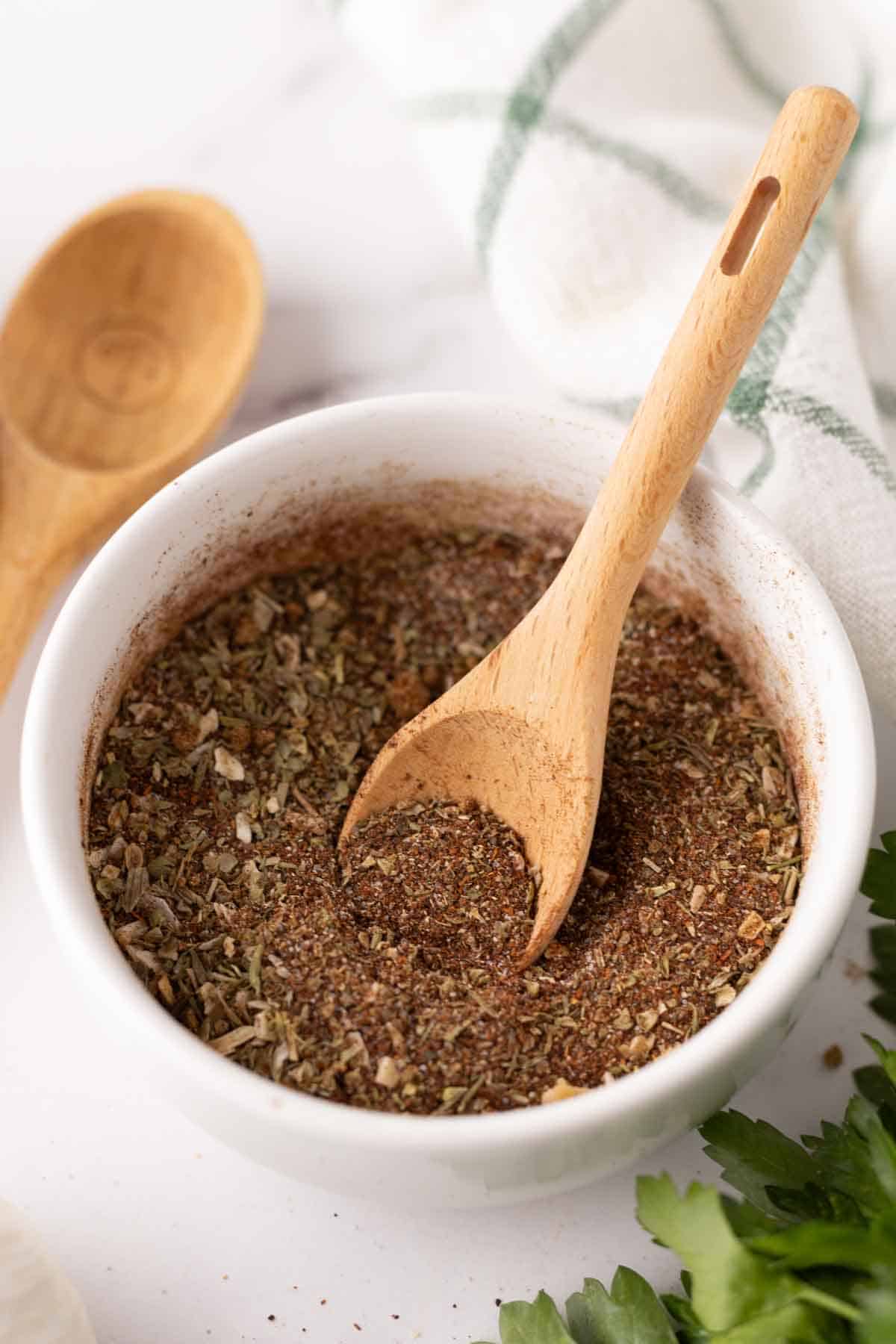 small white bowl with chili seasoning and a cute wooden spoon.