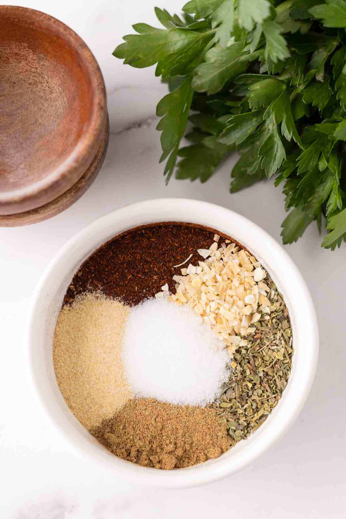 small white bowl with chili seasoning ingredients separated by color.