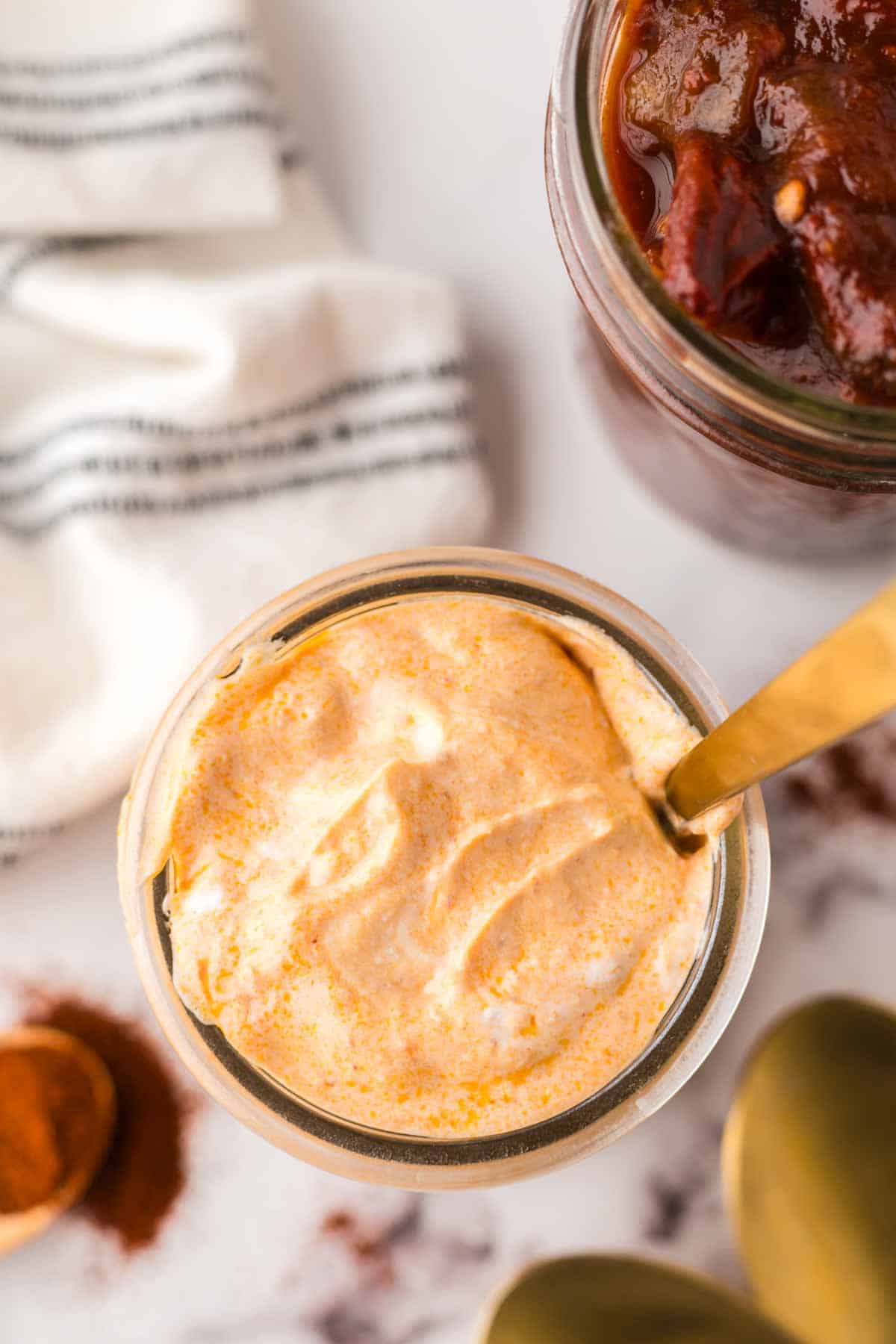 small glass jar of chipotle sauce with a golden spoon in it.