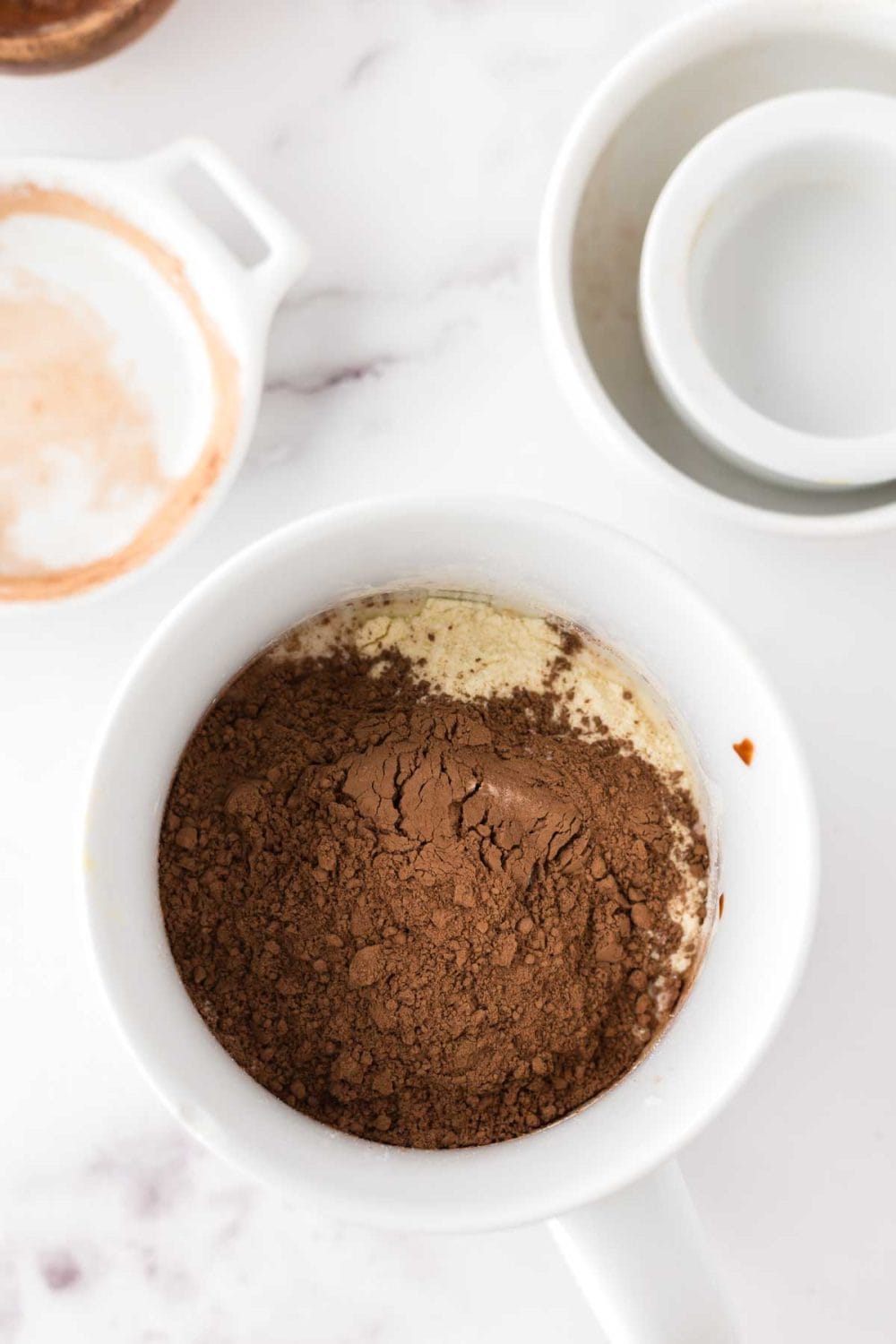 Chocolate cake batter in progress in a white coffee mug.