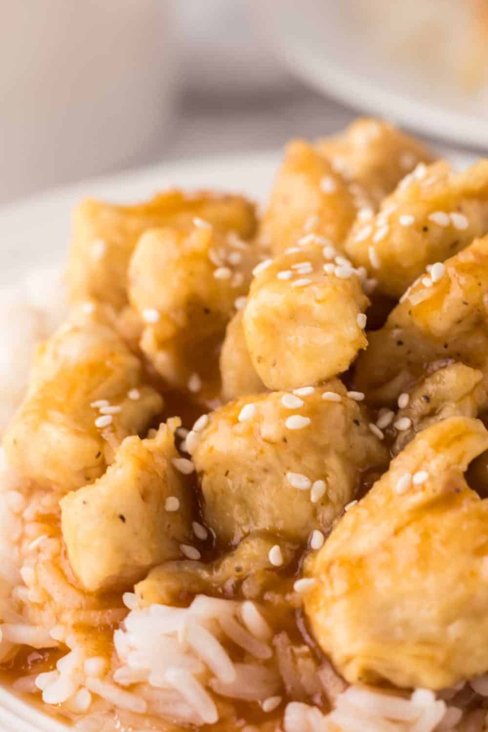 sweet and sour chicken over rice on a white plate.