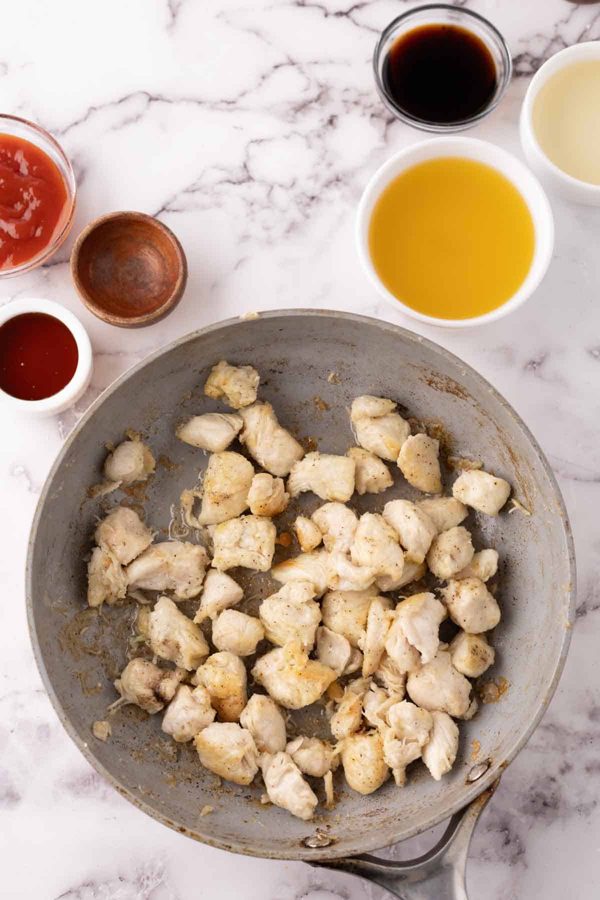 sautéed pan filled with in progress ingredients for sweet and sour chicken recipe.