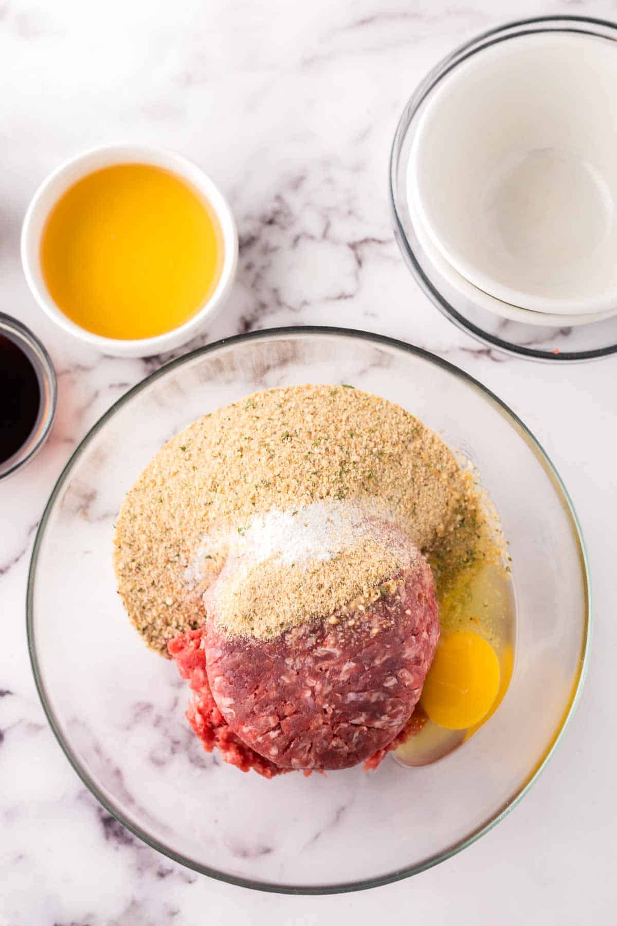 clear bowls with raw ingredients to make meatballs.