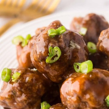 Stack of sweet and sour meatballs on a round white plate.
