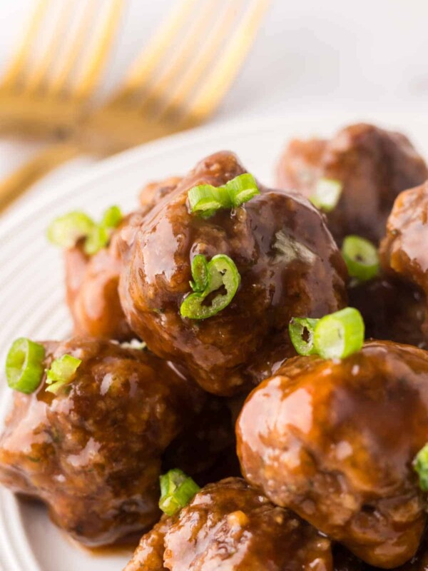 Stack of sweet and sour meatballs on a round white plate.