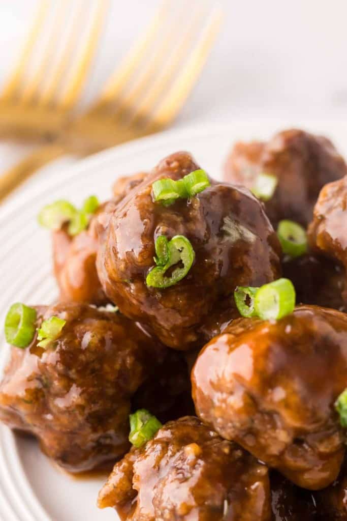 Stack of sweet and sour meatballs on a round white plate.