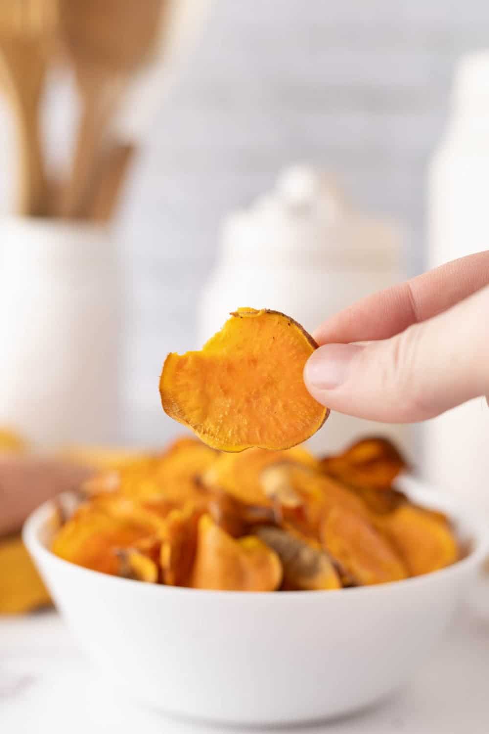 hand holding a sweet potato chip.