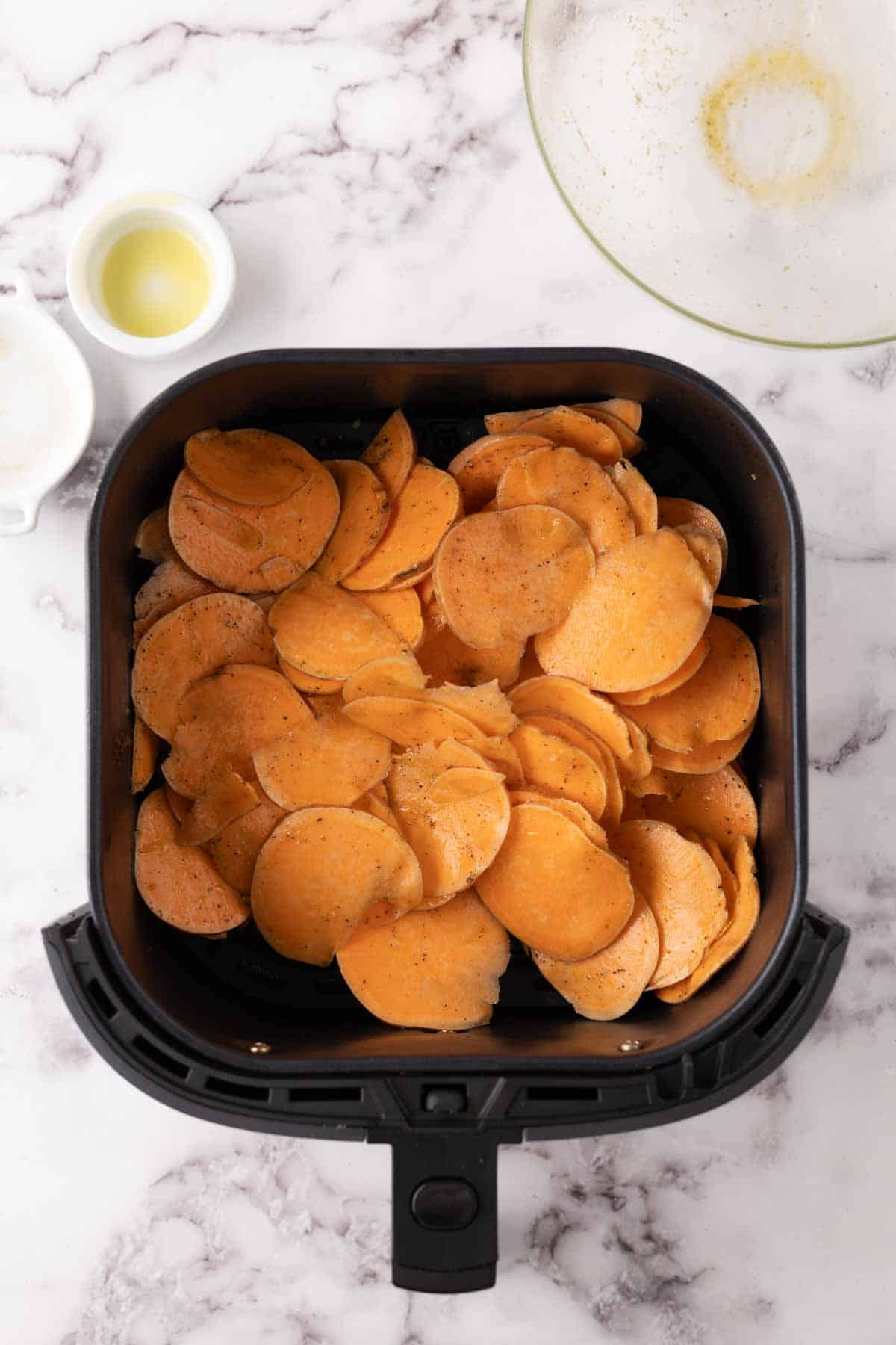 sweet potato chips in process inside a black air fryer basket.