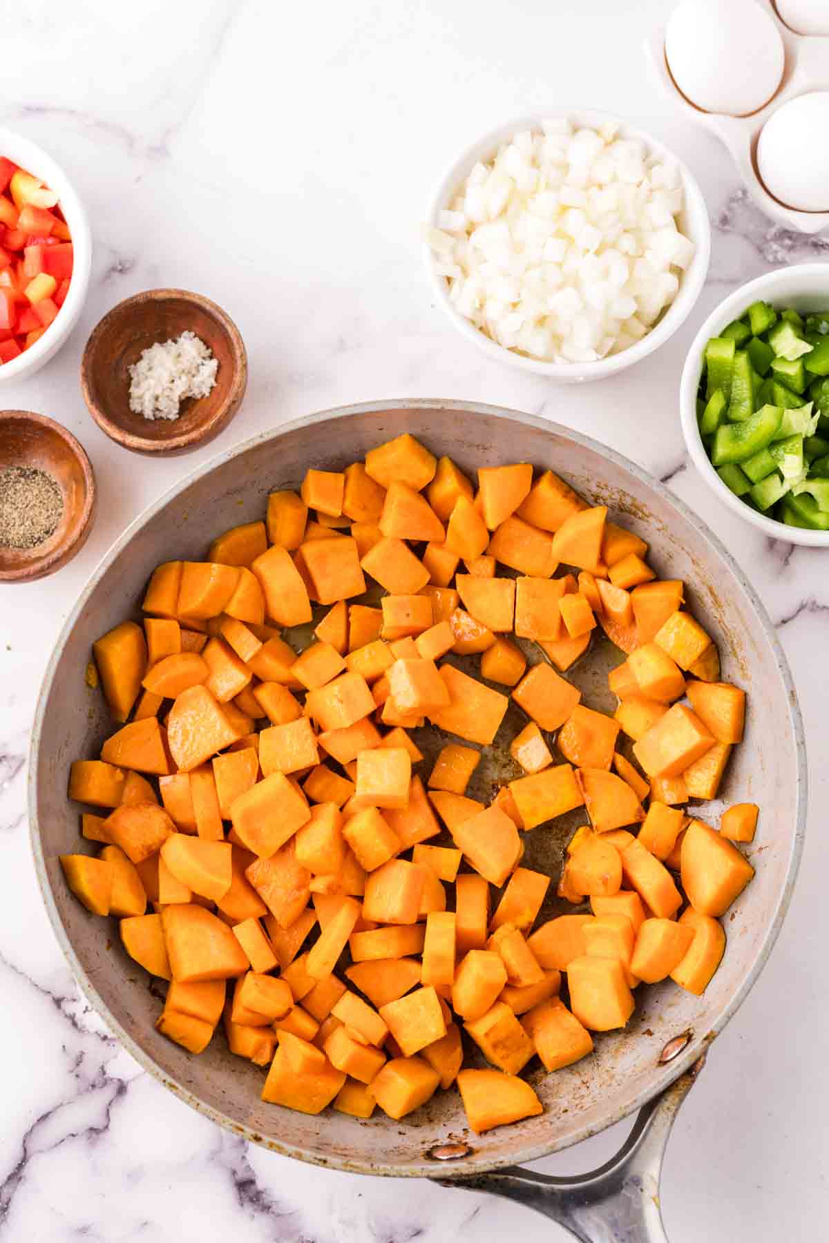 pan and portion dishes of raw vegetables for sweet potato hash before cooking.