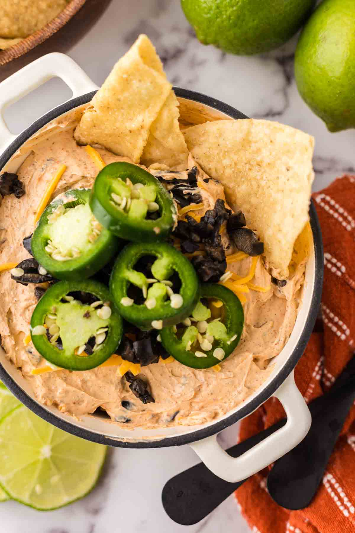 white bowl of a taco dip topped with sliced fresh jalapeños.