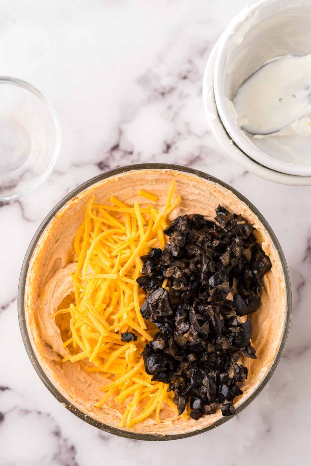 clear mixing bowl with whipped Taco Dip with cheese in progress.