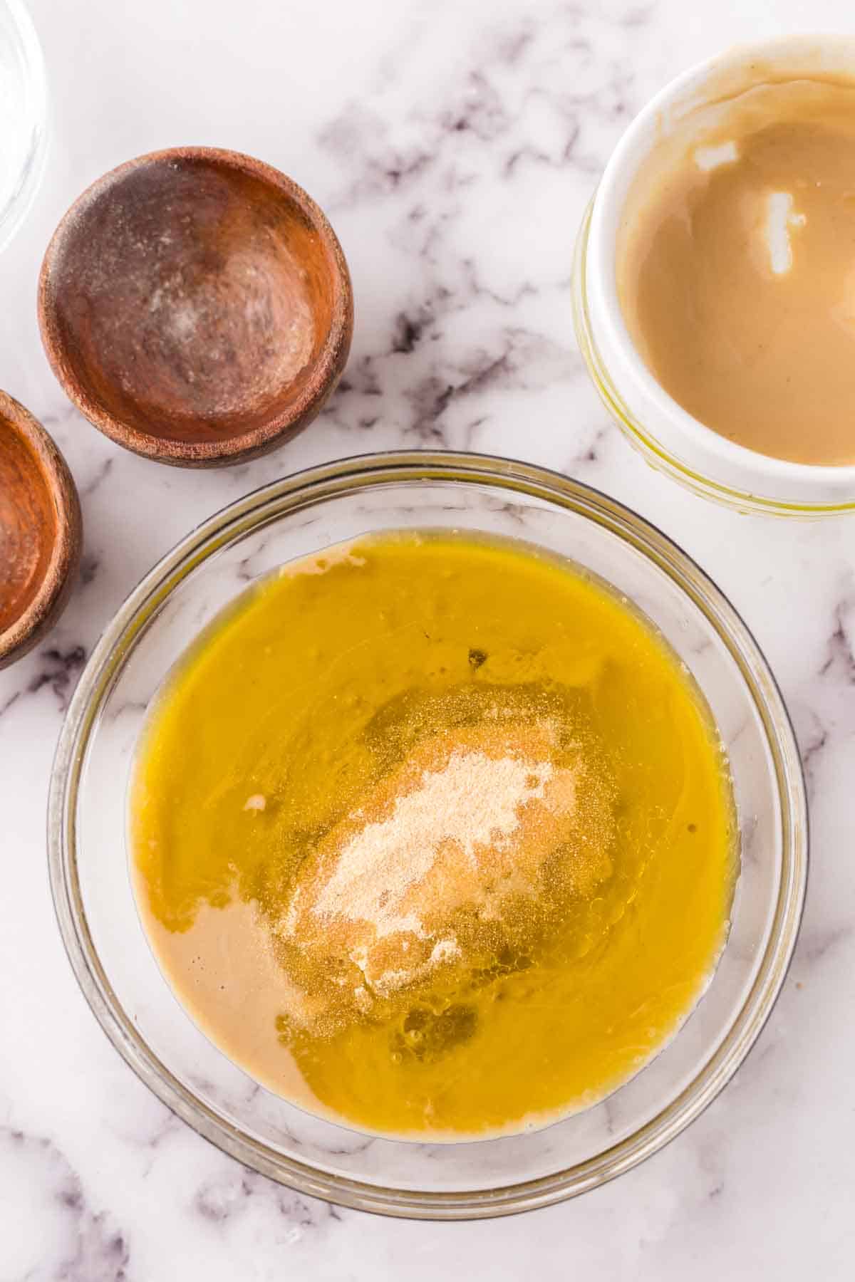 tahini dressing in clear glass mixing bowl ingredients in progress.