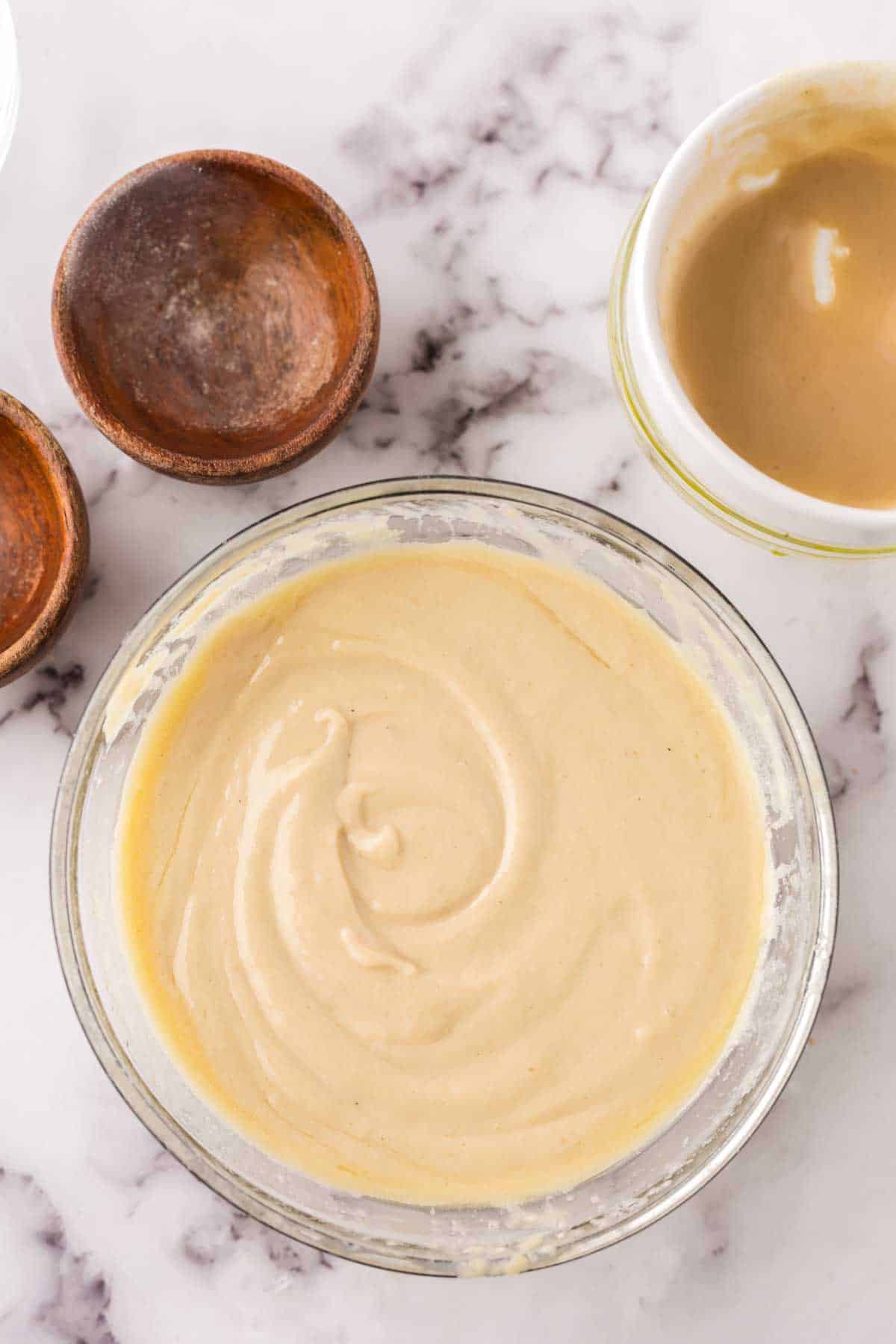 tahini dressing in clear glass mixing bowl ingredients in progress.