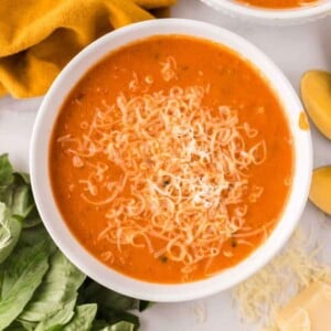 a bowl of tomato basil soup and cheese on top.