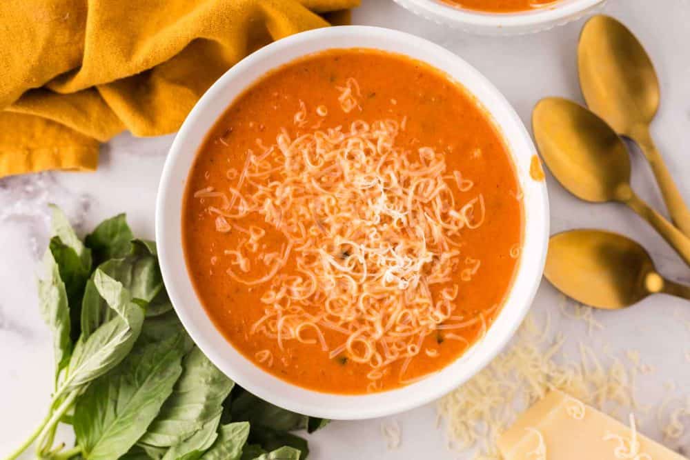 a bowl of tomato basil soup and cheese on top.
