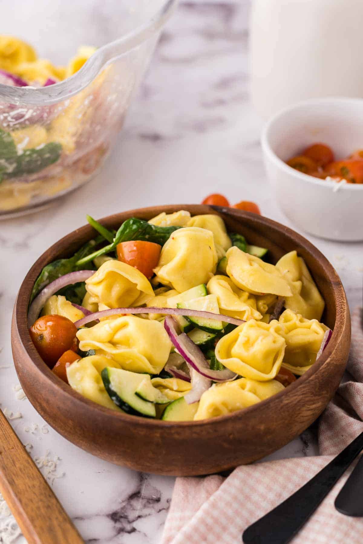 tortellini salad in a round wooden bowl.