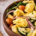 tortellini salad in a round wooden bowl.