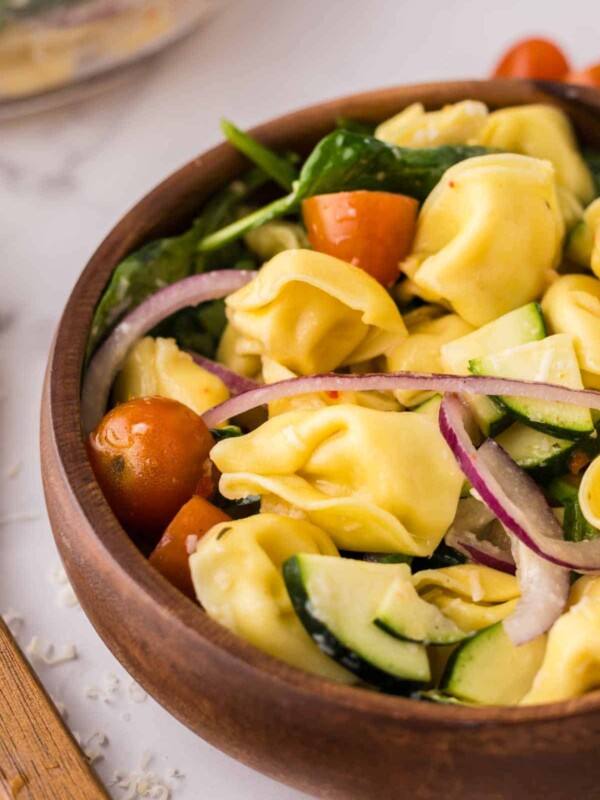 tortellini salad in a round wooden bowl.