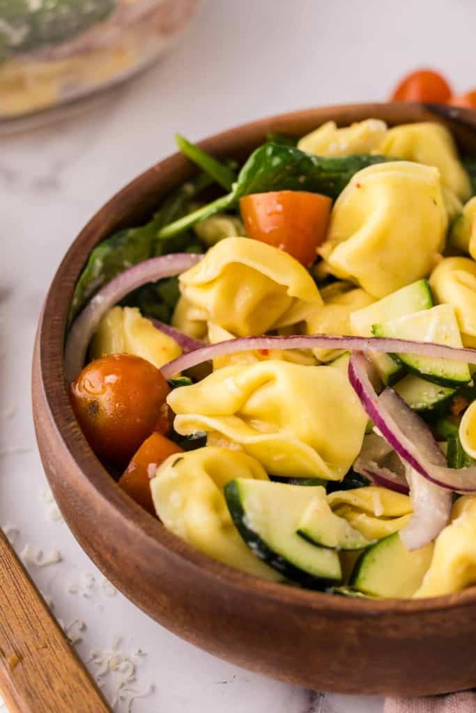 tortellini salad in a round wooden bowl.