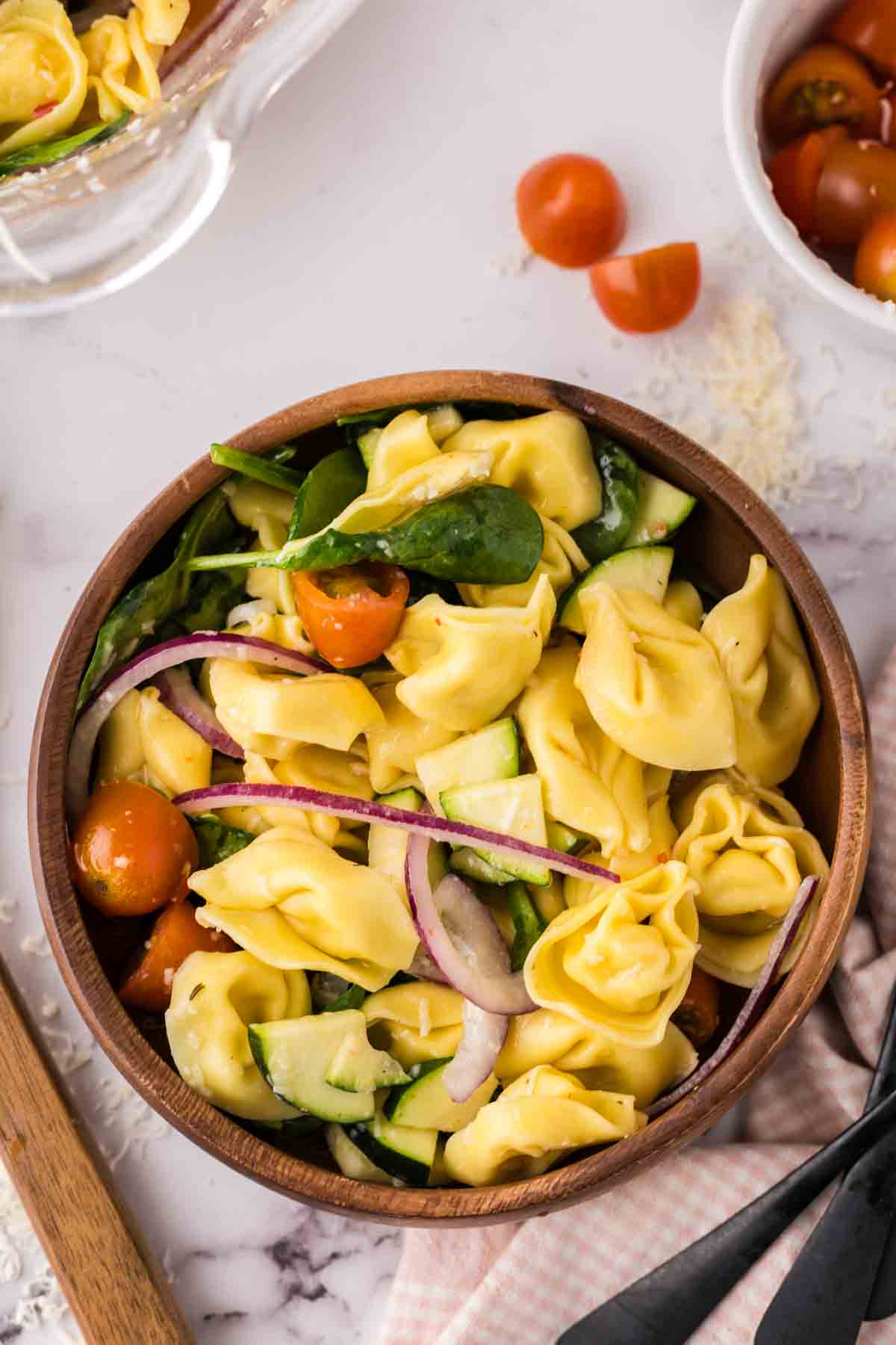 tortellini salad in a round wooden bowl.