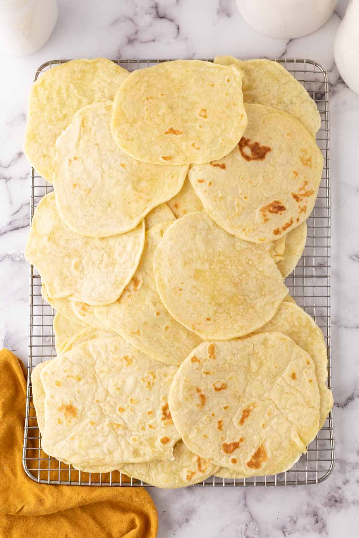 homemade tortillas piled onto a cooling rack.