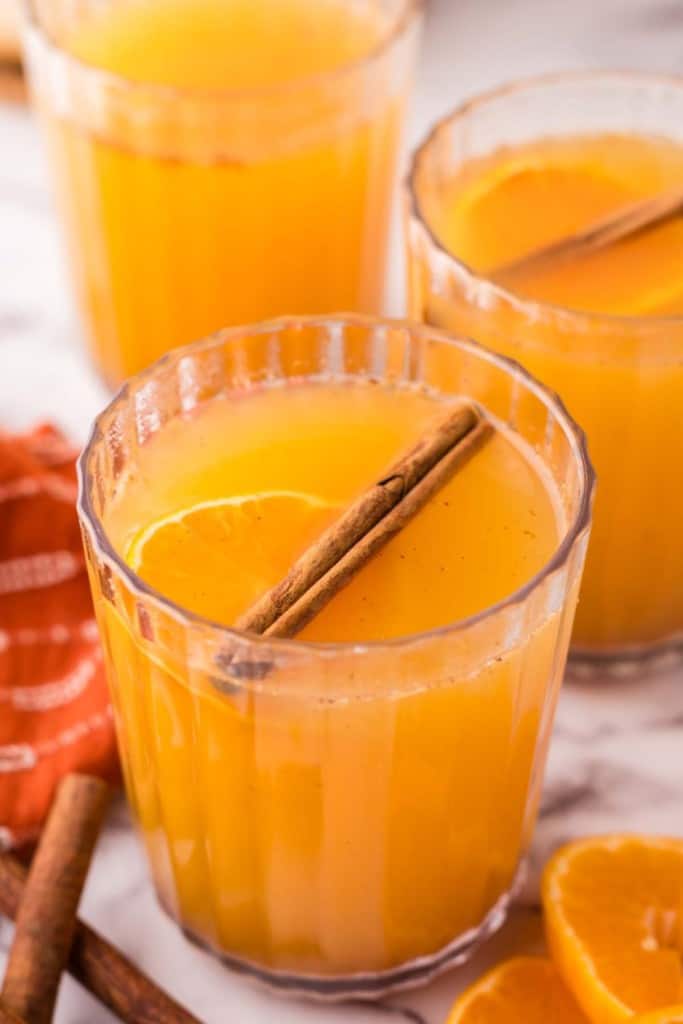 Glasses of wassail with cinnamon sticks.