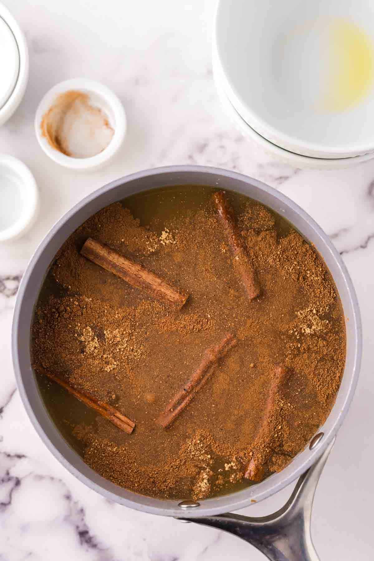 Combining all of the wassail ingredients into a pot.