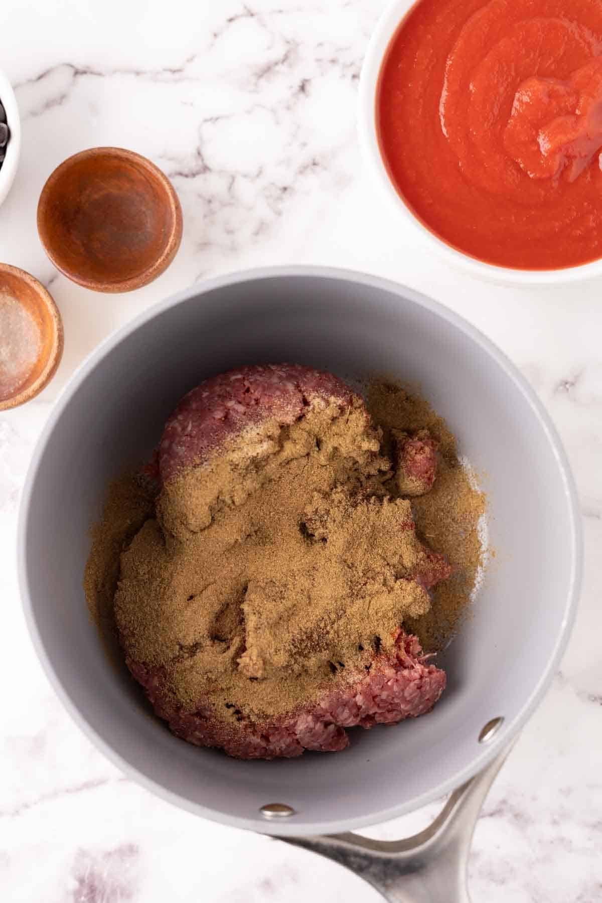 Ground beef mixed with spices in a bowl. 