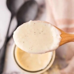 wooden spoon over a small glass jar with white pizza sauce.