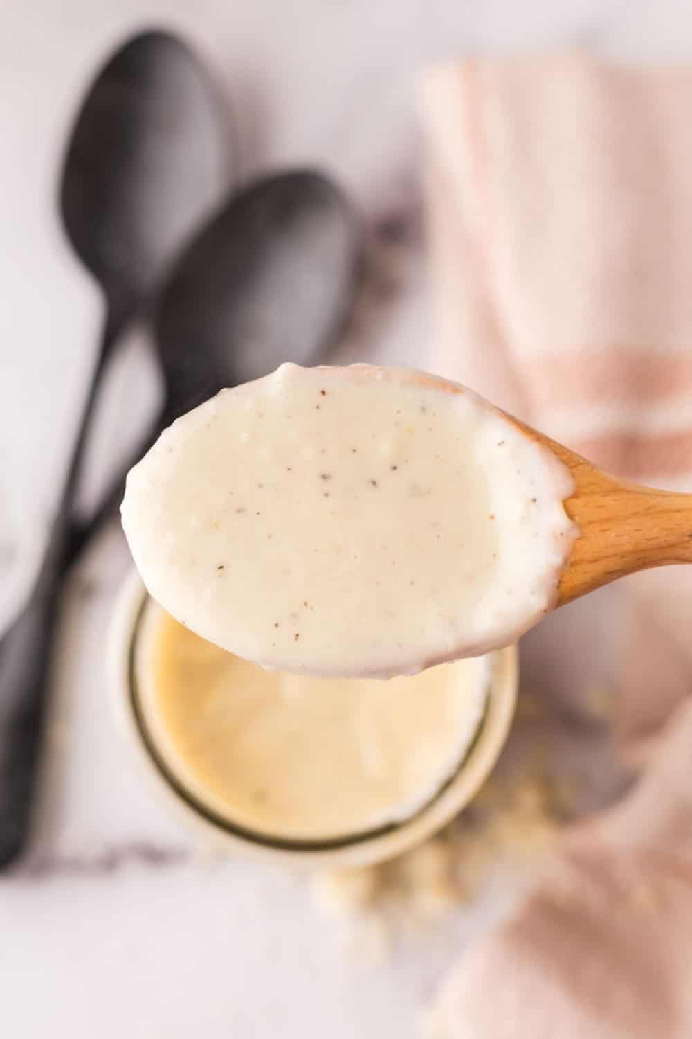 wooden spoon over a small glass jar with white pizza sauce.