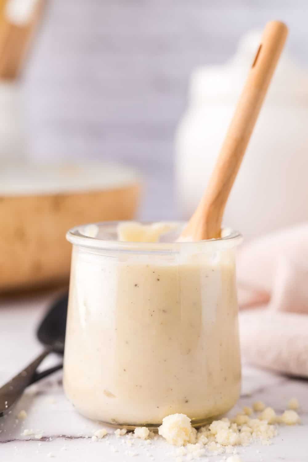 wooden spoon inside a small glass jar of white pizza sauce.
