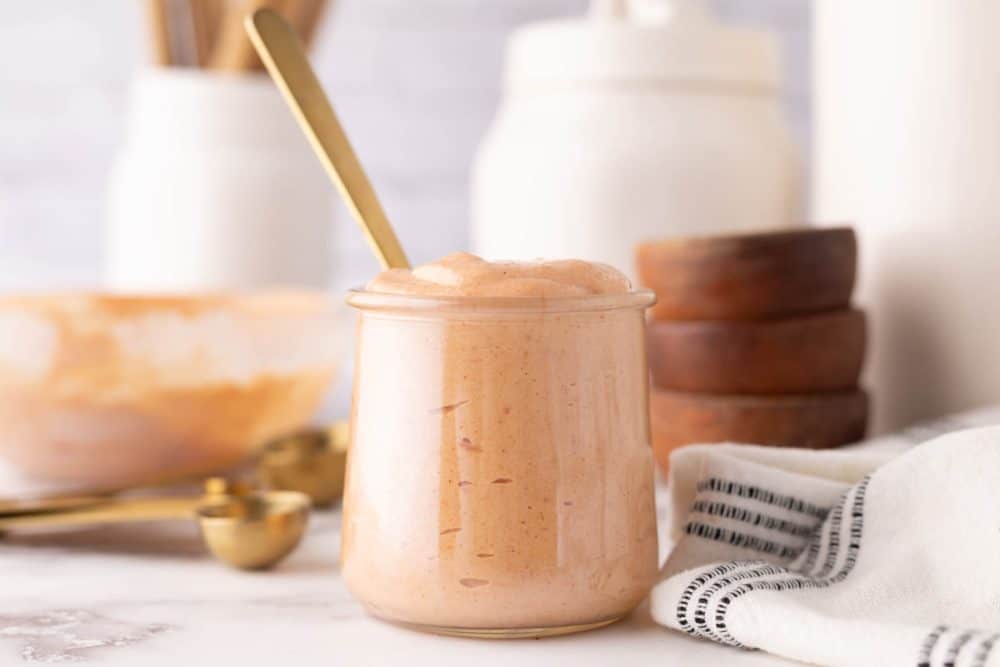 Yum Yum Sauce in a small glass jar with a golden spoon in it.